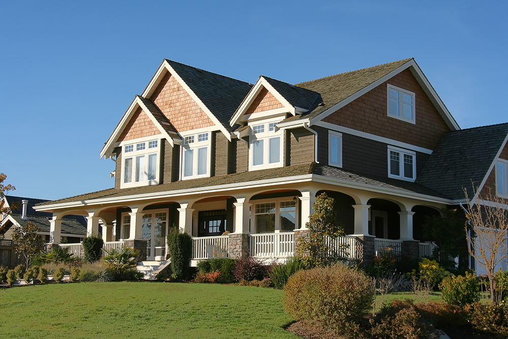 Exterior of large two-storey home with cedar siding and wrap around porch