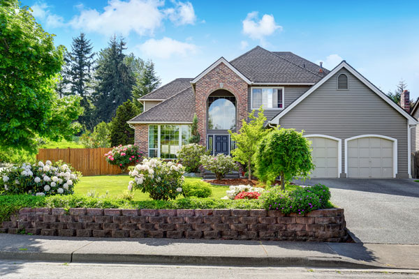 Exterior of large brick and grey two-storey home with gardens