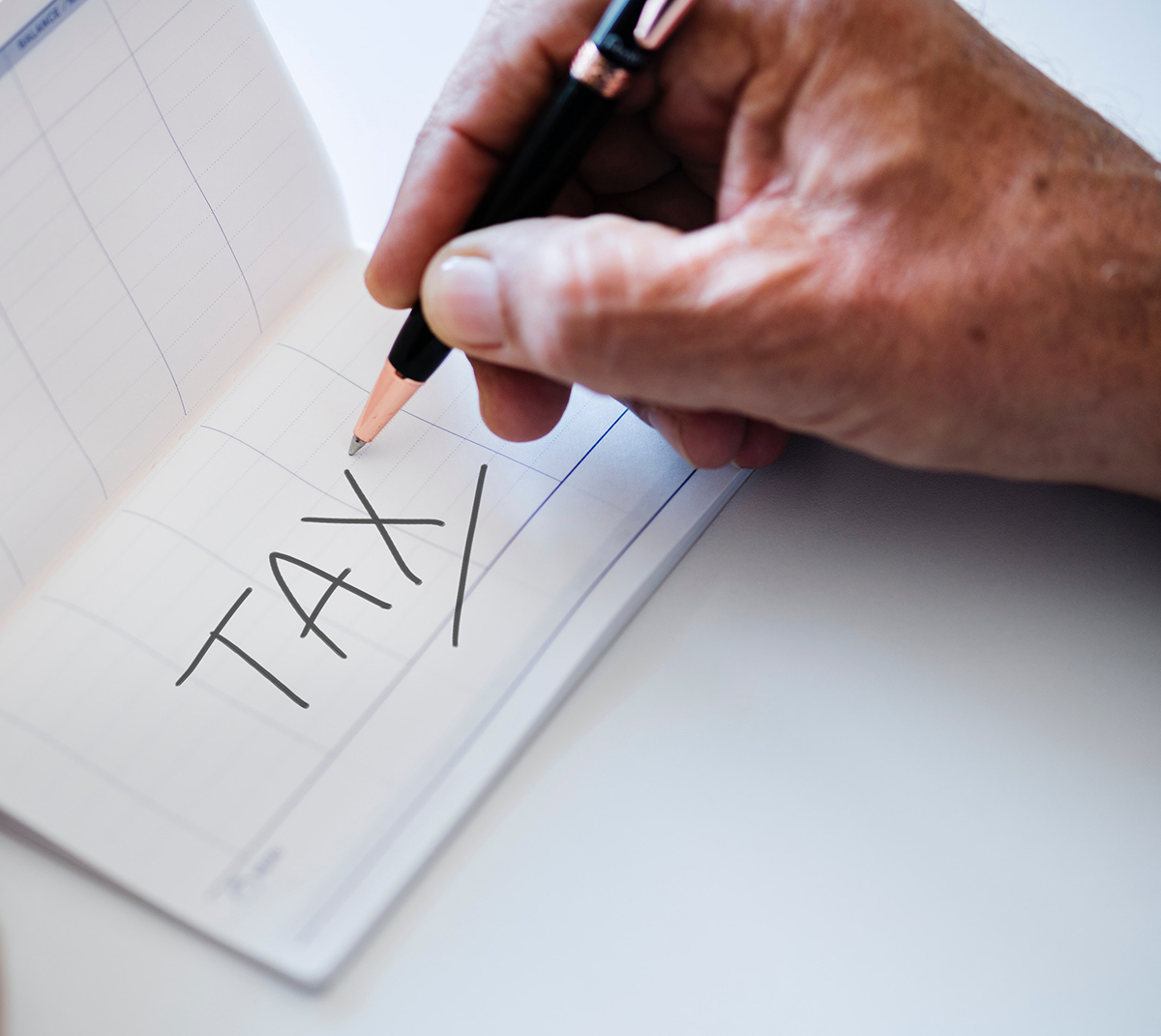 hand writing the word tax in large letters on a Calendar