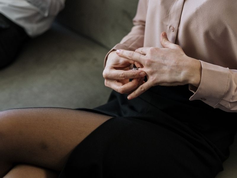 Women sitting on couch away from husband taking her wedding ring off