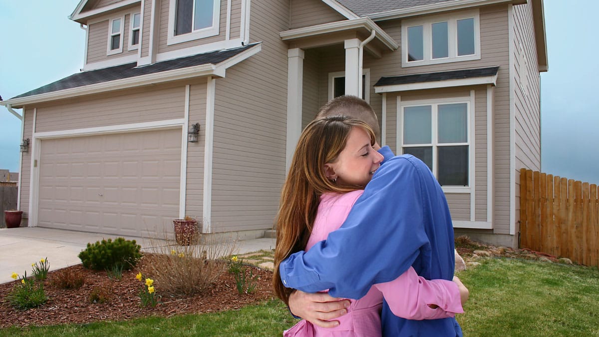 Couple hugging while in front of their new home